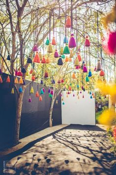 an outdoor ceremony with colorful tassels hanging from the trees