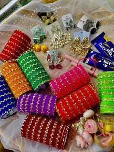 many different colored bracelets on a table with flowers and other items in the background