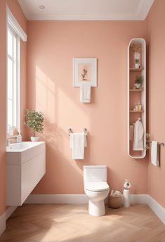 a white toilet sitting next to a sink in a bathroom under a window on top of a hard wood floor