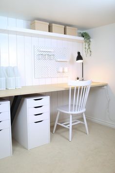 a white chair sitting in front of a desk with drawers and a lamp on it