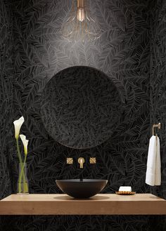 a bathroom with a sink, mirror and towel rack in front of black wallpaper