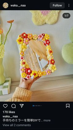 a person holding up a mirror with flowers on it