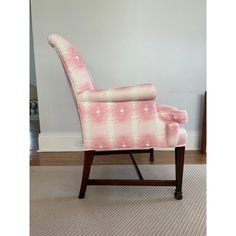 a pink and white chair sitting on top of a carpeted floor next to a wall