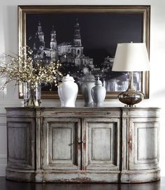 a table with vases and flowers on it in front of a large framed photograph