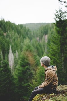 a person sitting on top of a hill with trees in the background and text overlay