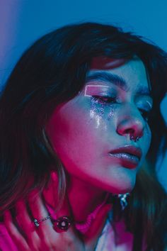 a woman with glitter on her face and eyeliners is posing for a photo