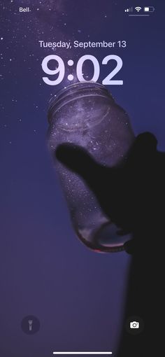 a hand holding a glass jar with the date 9 002 on it and stars in the background