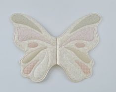 a white butterfly with pink and green patches on it's wings