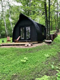 a small black cabin sitting in the middle of a forest