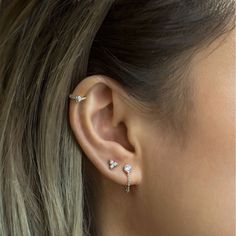 a close up of a woman's ear with three small diamond studs