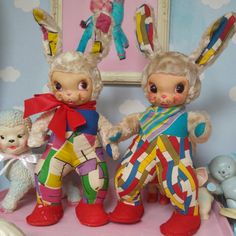 two dolls are standing next to each other in front of a wall with pictures on it