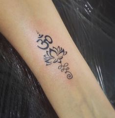 a small tattoo on the arm of a woman with an om symbol in black ink