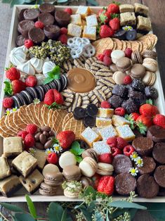 a platter filled with lots of different types of desserts and pastries on top of a wooden table