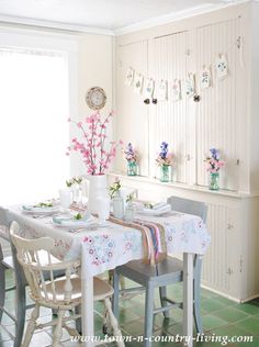 a dining room table and chairs with flowers in vases on the wall behind them