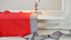 a red and grey blanket is next to a sewing machine with the needle on it