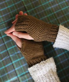 two hands in knitted mittens holding each other's fingers on a plaid table cloth