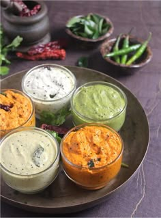 four small bowls filled with different types of dips and sauces on a plate