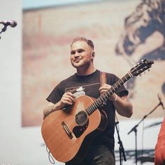 a man holding an acoustic guitar on stage