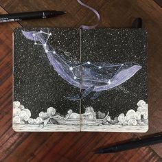 a notebook with a drawing of a whale and stars in the night sky on it