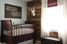 a baby's room with a crib and deer head mounted on the wall