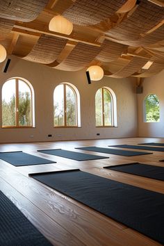 yoga mats are lined up on the floor in an empty room with large arched windows