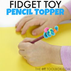 a child is using scissors to make a paper topper with pom - poms