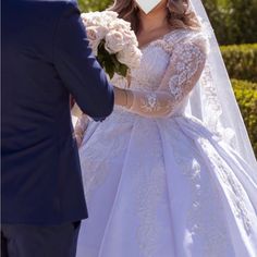 a woman in a wedding dress is holding a bouquet and standing next to a man wearing a tuxedo