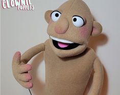 a brown stuffed animal with big eyes holding a microphone and giving the thumbs up sign