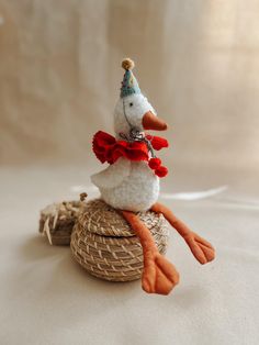 a stuffed duck wearing a party hat and bow tie sitting on top of a wicker basket