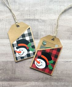 two tags with snowmen on them are hanging from twine strings and decorated with christmas decorations