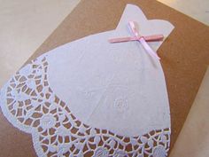 a card with a white dress on it and a pink ribbon tied to the front