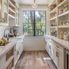 a kitchen with lots of white cabinets and wood flooring on the counter tops, along with open shelving