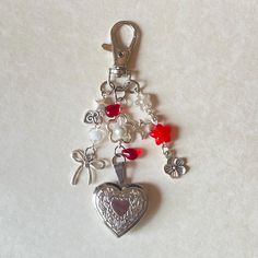 a heart shaped keychain with charms attached to it on a white table top