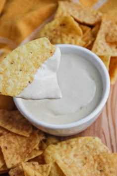 a tortilla chip being dipped with sour cream surrounded by tortilla chips