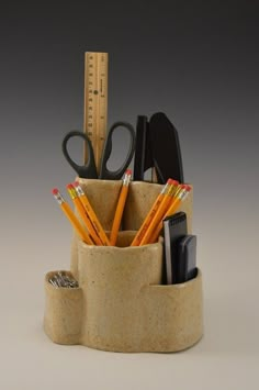 a cup with pencils, scissors and pens in it next to a tape dispenser