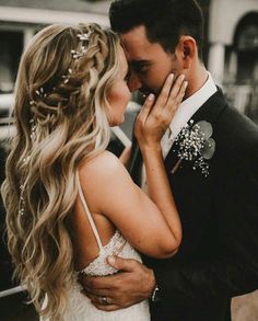 a man in a suit and tie kissing a woman's face with her hand on her cheek