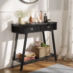 a black console table with drawers and candles on it in front of a white wall