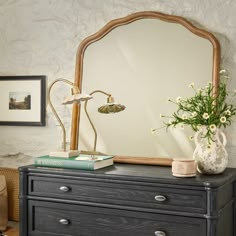 a dresser with a mirror and flowers on it