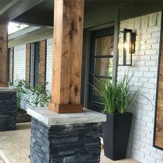 an outside view of a house with some plants on the front porch and two large black planters