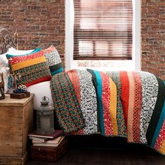 a bed sitting next to a window with a blanket and pillows on top of it