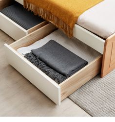 a bed with two drawers underneath it and a blanket on the bottom one drawer is open