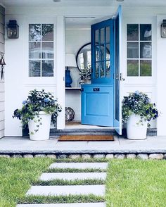 an instagram photo with blue door and flowers on the front steps in front of a house