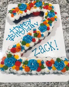 a birthday cake shaped like the letter z with flowers on it and happy birthday written in blue frosting