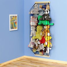 a birdcage filled with stuffed animals on top of a wooden floor next to a blue wall