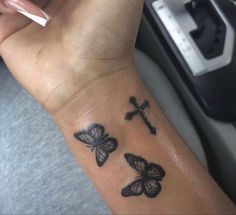 a woman's arm with three butterflies on it and a cross tattooed on the wrist