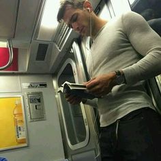 a man is looking at his cell phone while riding on the train with headphones