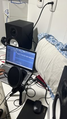 a laptop computer sitting on top of a desk next to headphones and speakers in a room