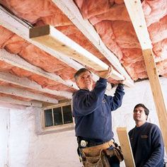 two men are working on the ceiling in an unfinished room with exposed wood beams and insulation