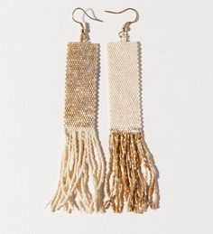 two pairs of gold and white beaded earrings with tassels hanging from them