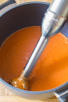 a metal bowl filled with red sauce and a mixer